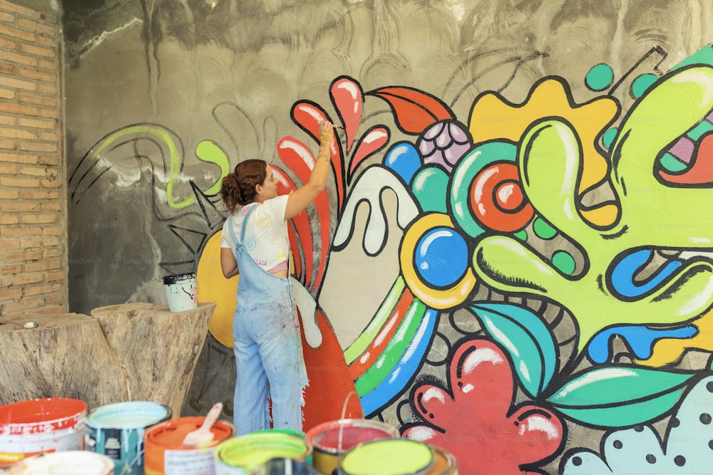 a woman painting a mural on the side of a building