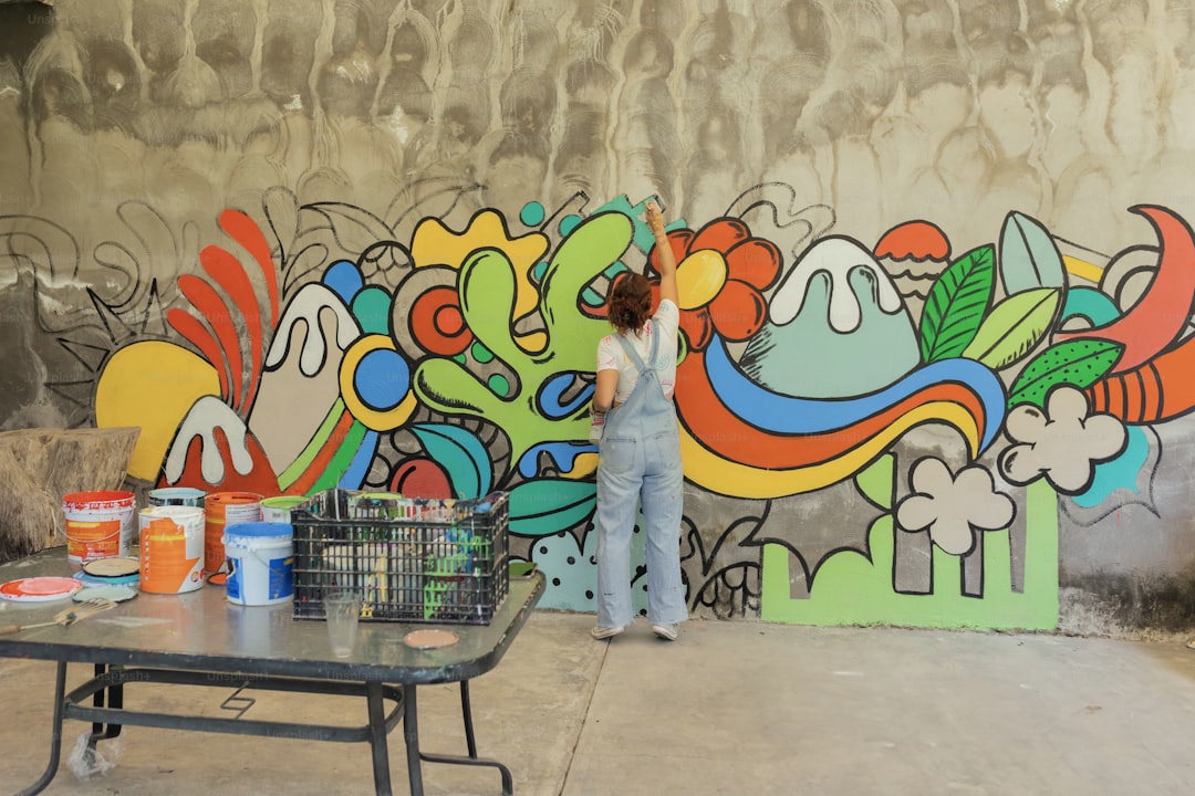 a woman painting a mural on the side of a building