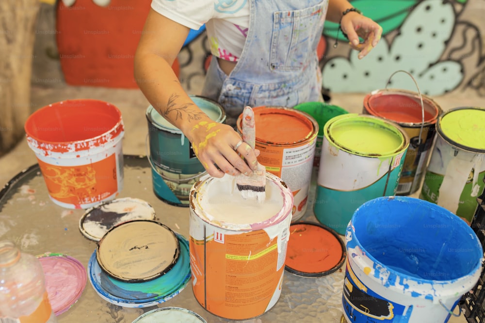 a woman is painting a bucket of paint on a table