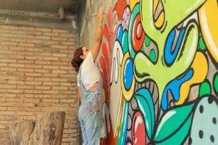 レンガの壁に壁画を描く女性