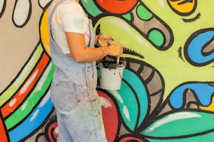 um homem pintando uma parede com um balde de tinta