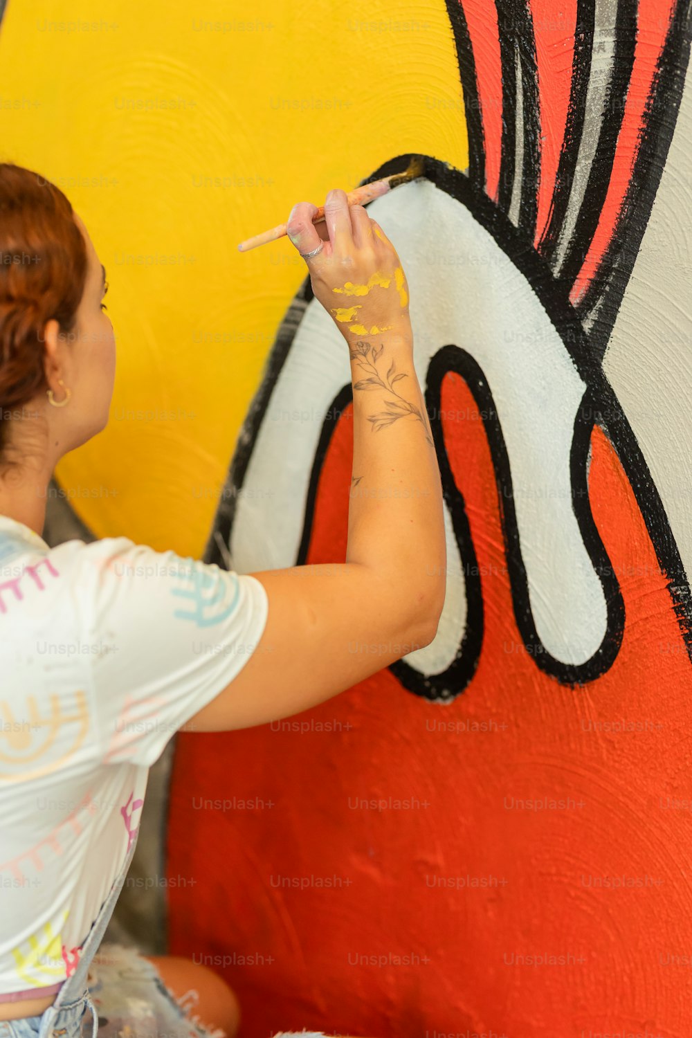 Una mujer pintando un mural en el costado de un edificio