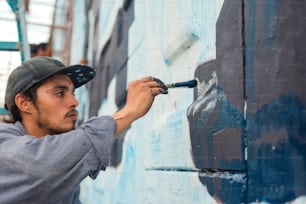 Ein Mann streicht eine Wand mit blauer Farbe
