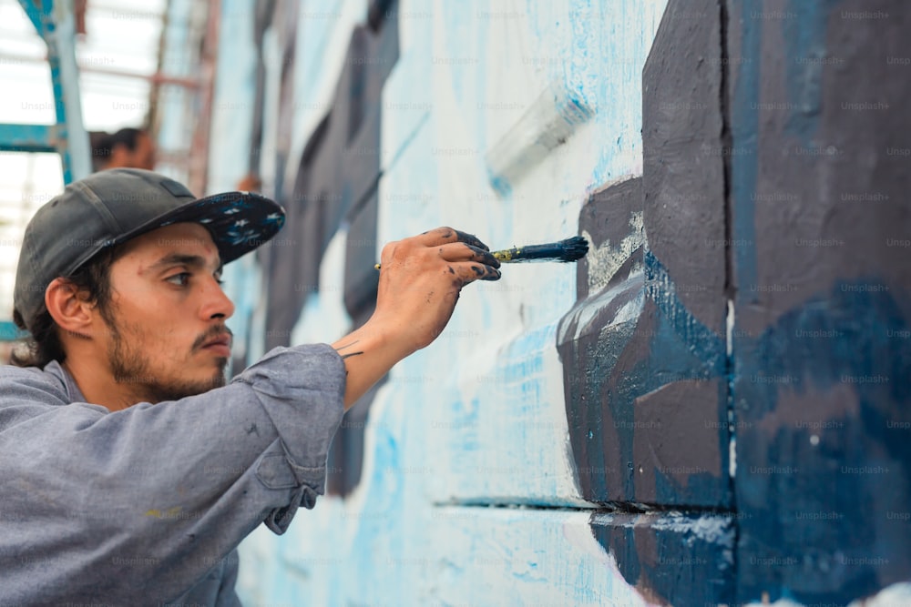 男が青いペンキで壁を塗っている