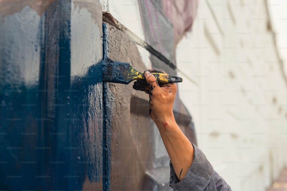 a person painting a wall with blue paint