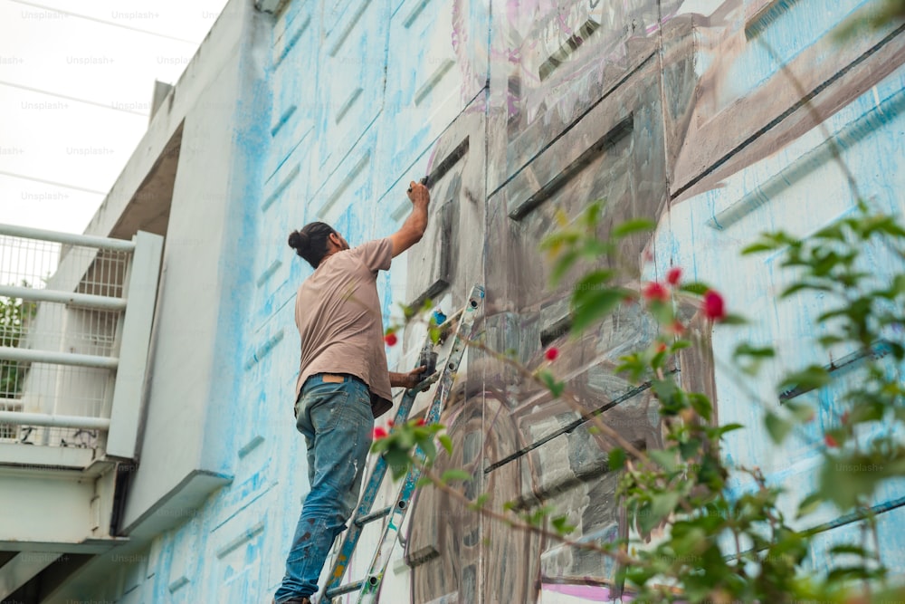 Un uomo sta dipingendo un murale sul lato di un edificio