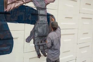 Un hombre pintando un mural en el costado de un edificio