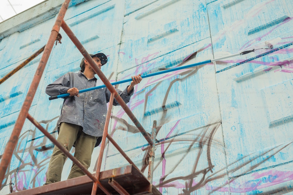 a man standing on a scaffolding in front of a blue wall