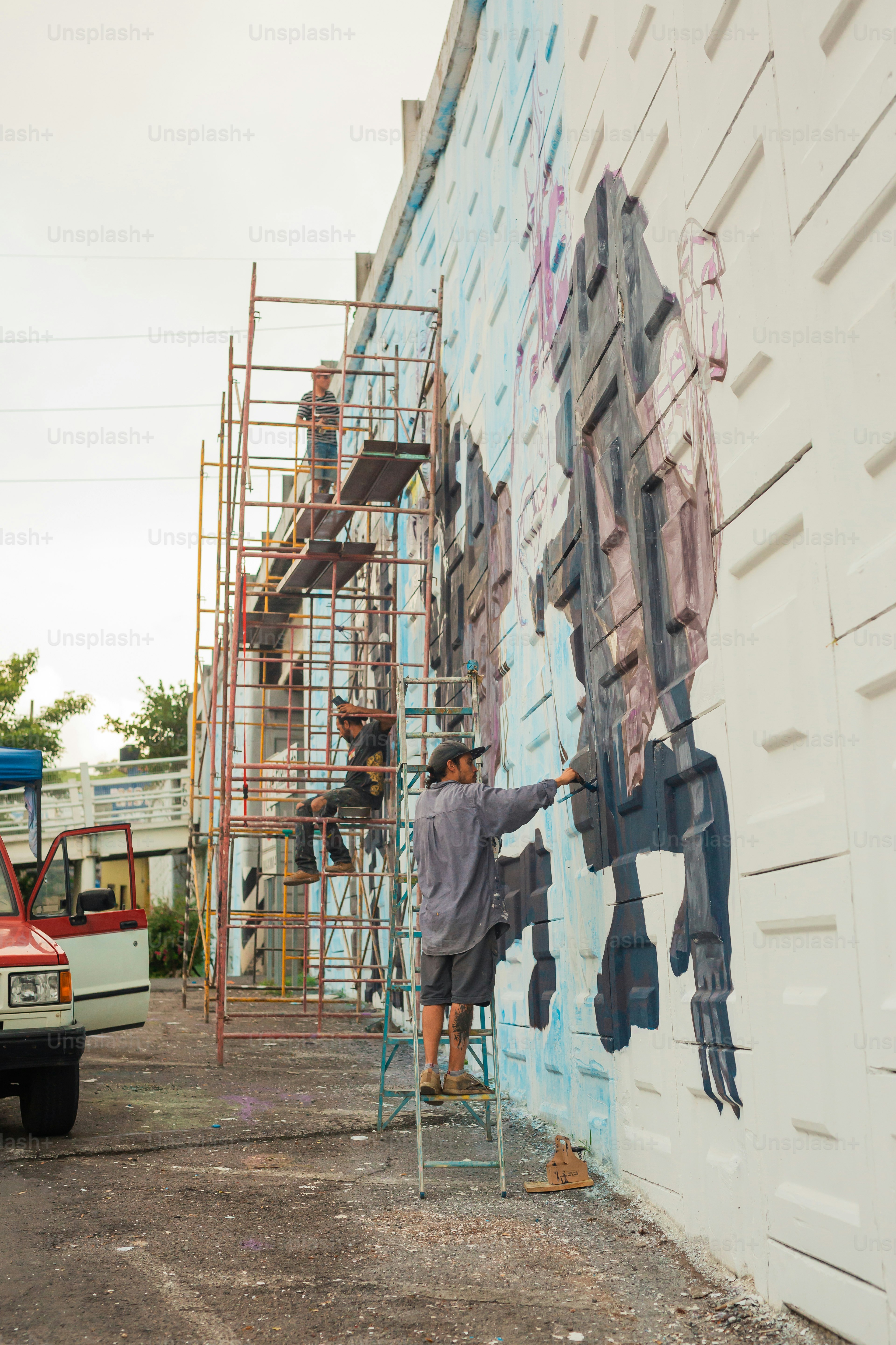 A man on a ladder painting a wall photo – Mural Image on Unsplash