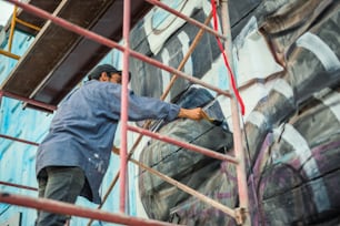 男が建物に壁画を描いている