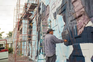 建物の側面に壁画を描く男