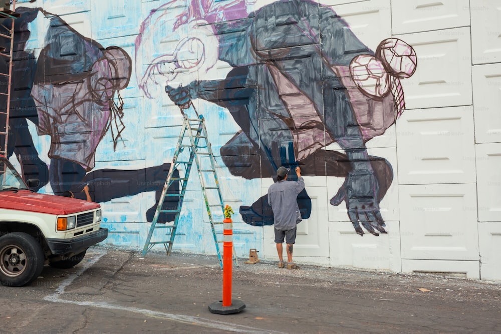 Un homme peignant une peinture murale sur le côté d’un bâtiment