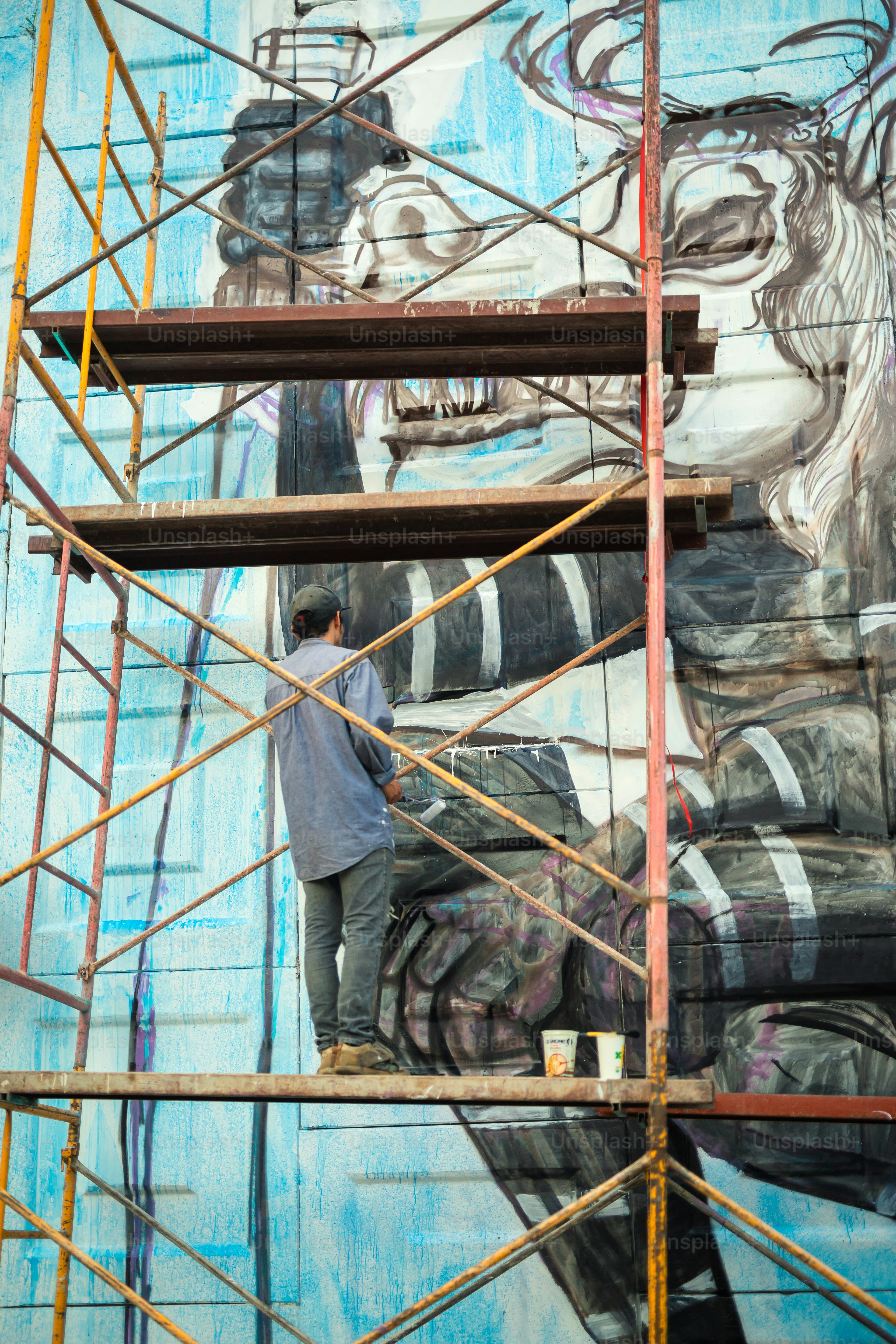 a man is painting a mural on the side of a building
