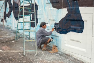 Un homme peignant un mur avec de la peinture bleue