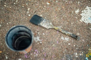 a paintbrush laying on the ground next to a paint can