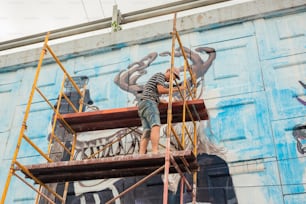 a man is painting a mural on the side of a building