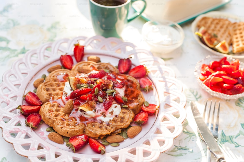 a plate of waffles with strawberries and whipped cream