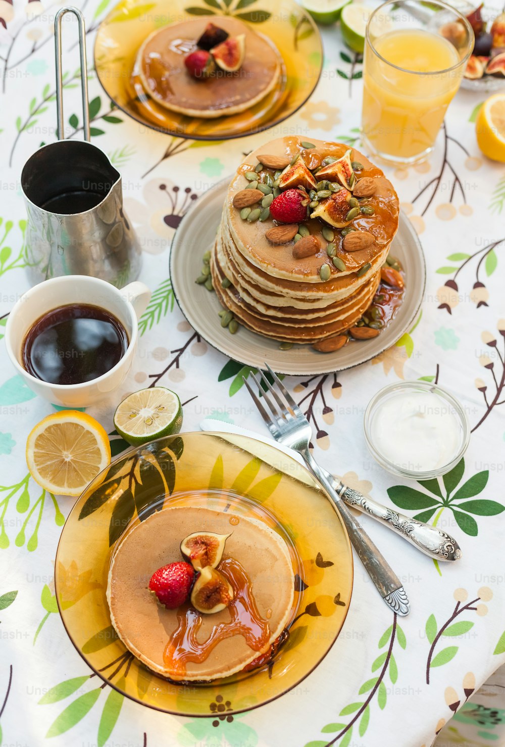 a table topped with pancakes covered in syrup and fruit