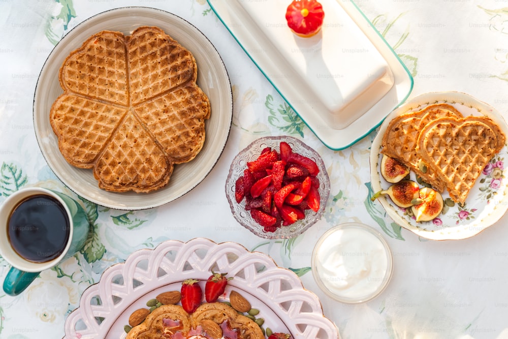 a table topped with plates of waffles and fruit