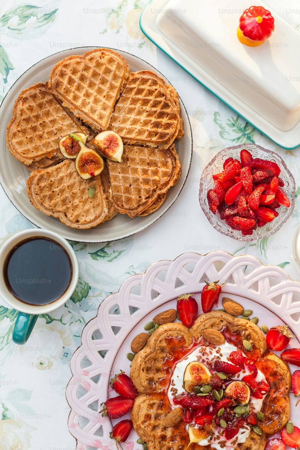 a table topped with waffles and fruit next to a cup of coffee