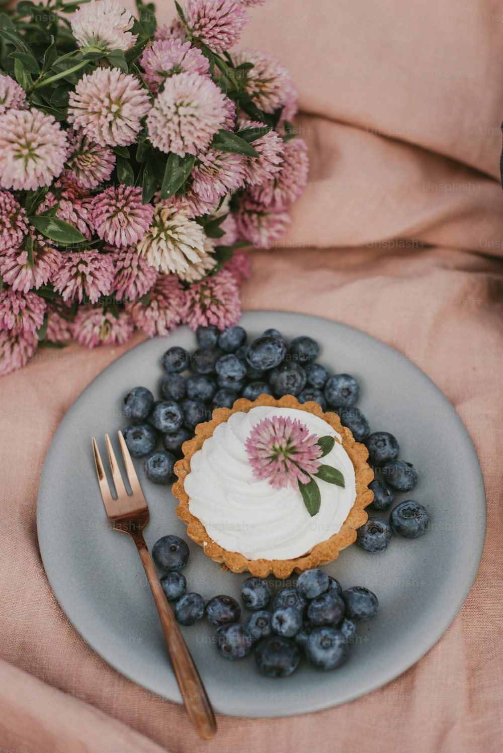 a blueberry tart on a plate with a fork next to it