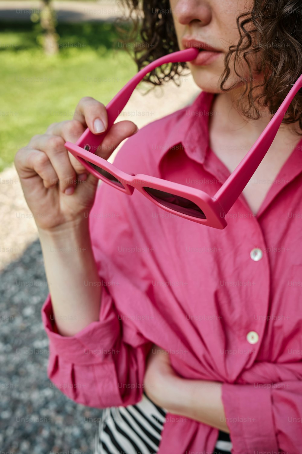 Une femme en chemise rose tient une paire de lunettes roses