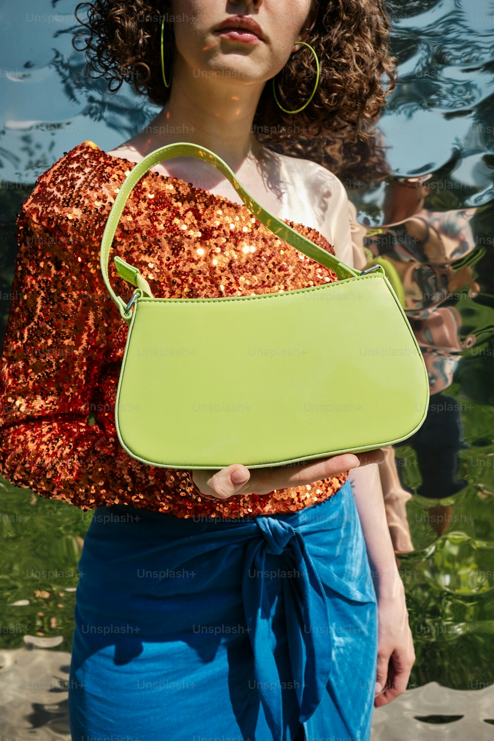 Una mujer sosteniendo un bolso verde en la mano