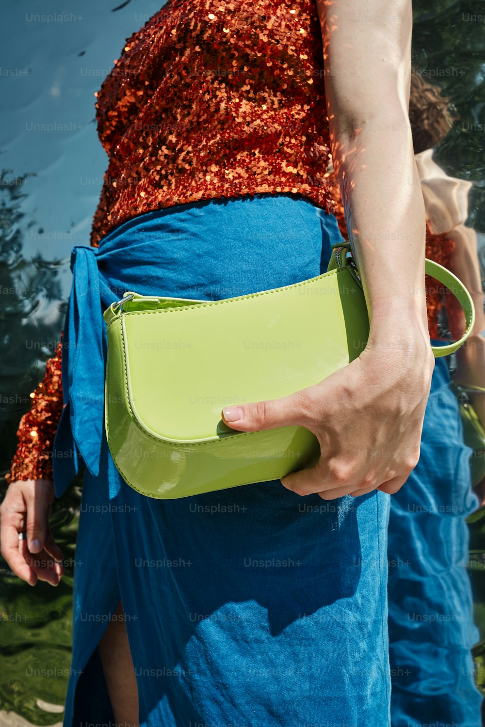 a woman in a blue dress holding a green purse
