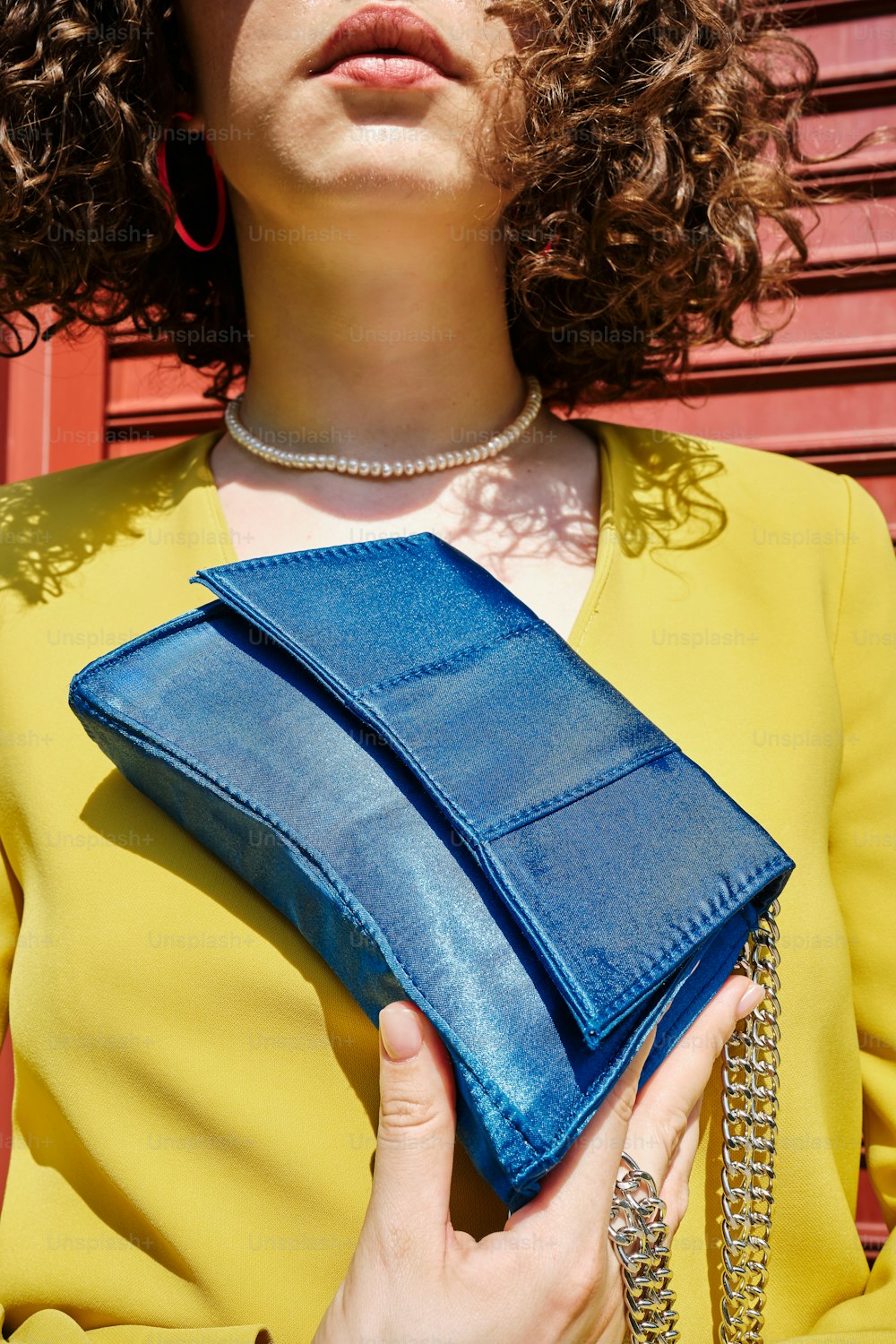 a woman with curly hair holding a blue purse