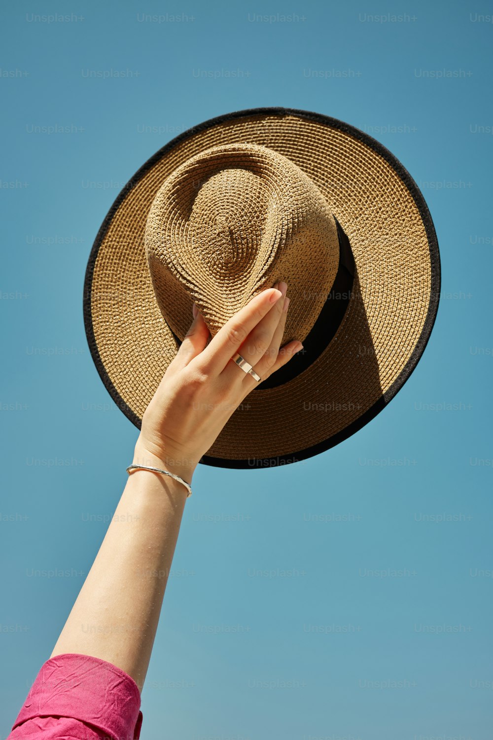 a woman's hand holding a hat up in the air