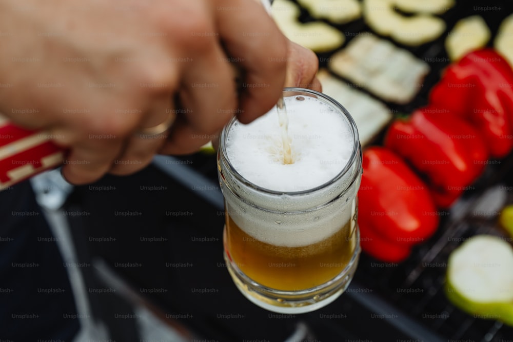 a person holding a glass of beer in their hand