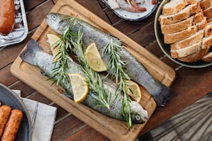 a fish on a cutting board with lemons and rosemary