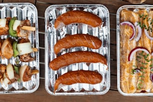 three metal trays filled with different types of food