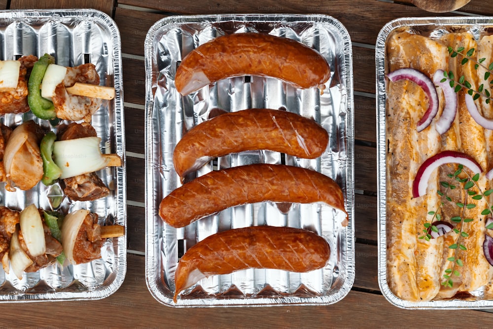 tre vassoi metallici riempiti con diversi tipi di cibo
