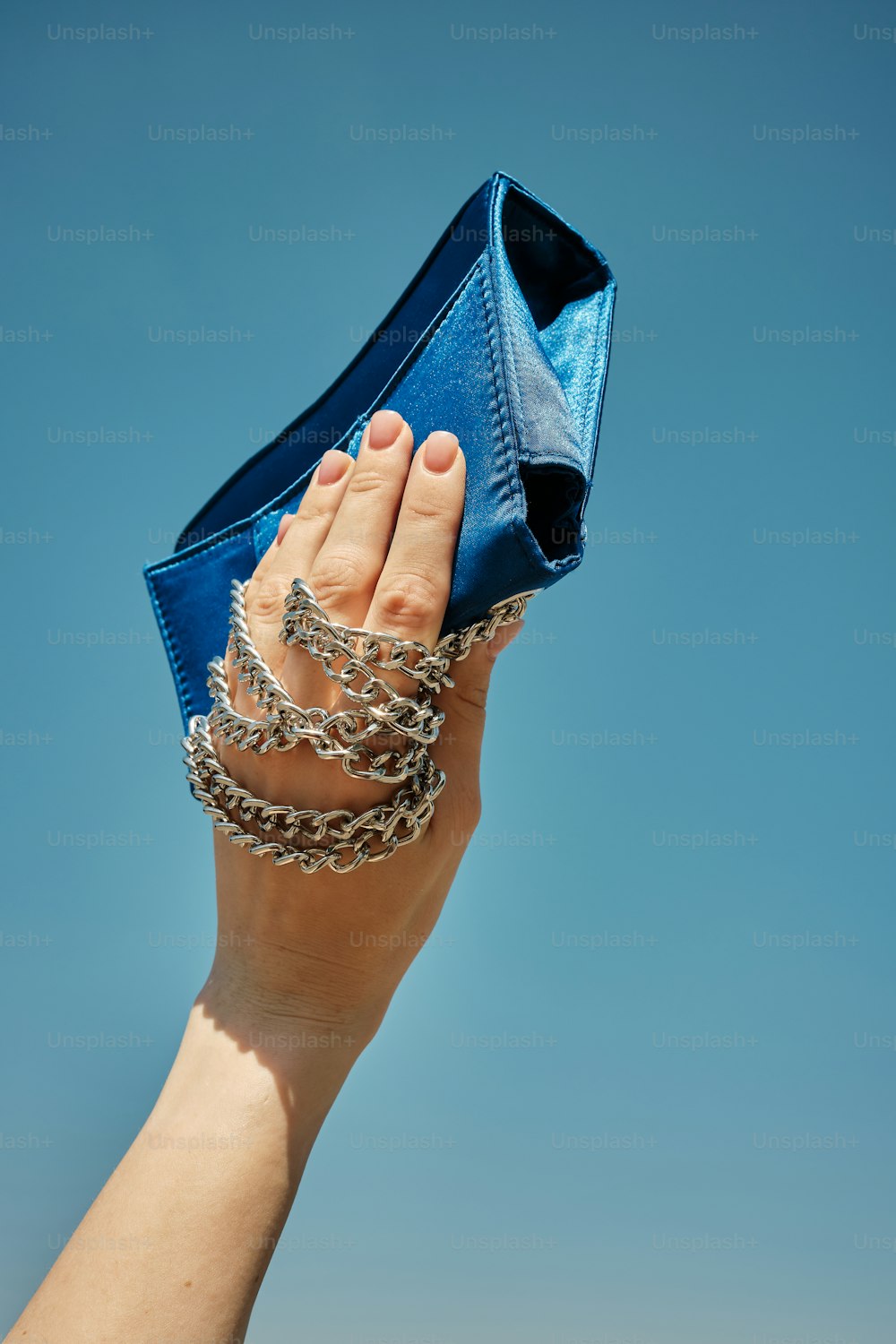la main d’une femme tenant un sac à main bleu