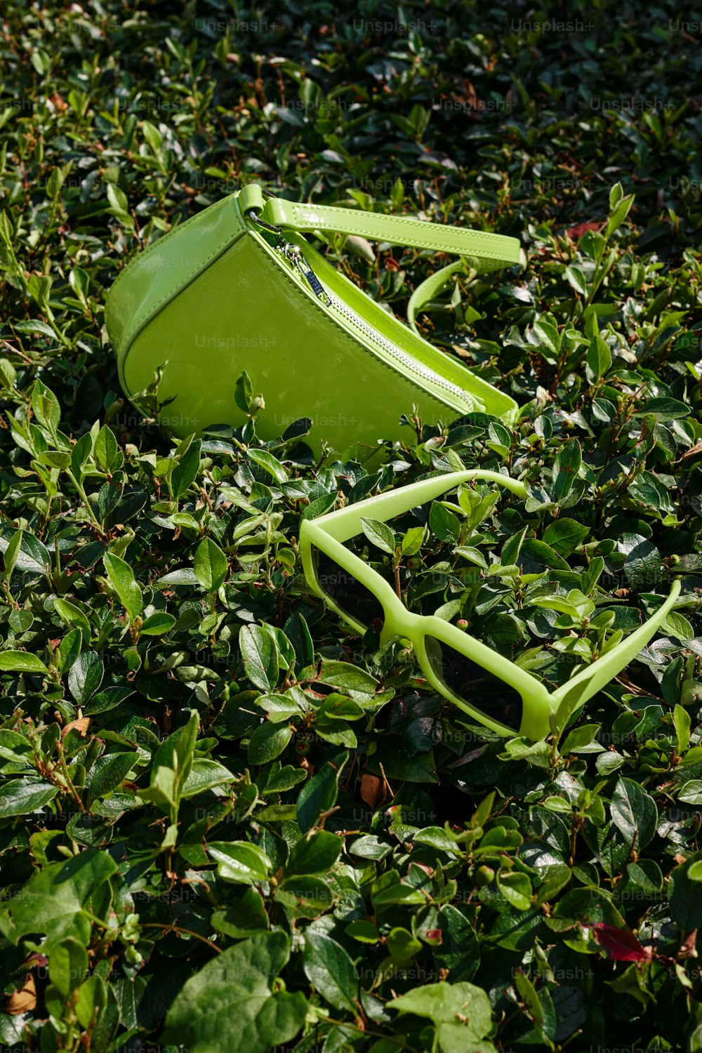 a green metal object laying on top of a lush green field