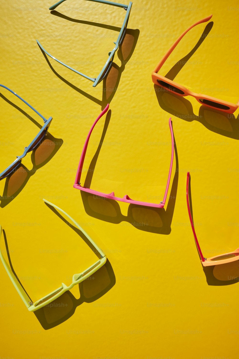 four pairs of sunglasses sitting on top of a yellow surface