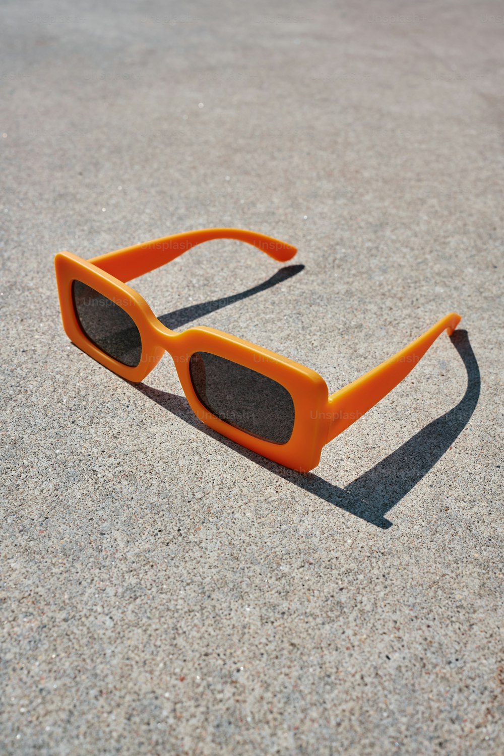 eine orangefarbene Sonnenbrille, die auf dem Boden liegt