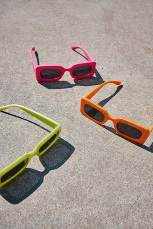 three pairs of sunglasses laying on the ground