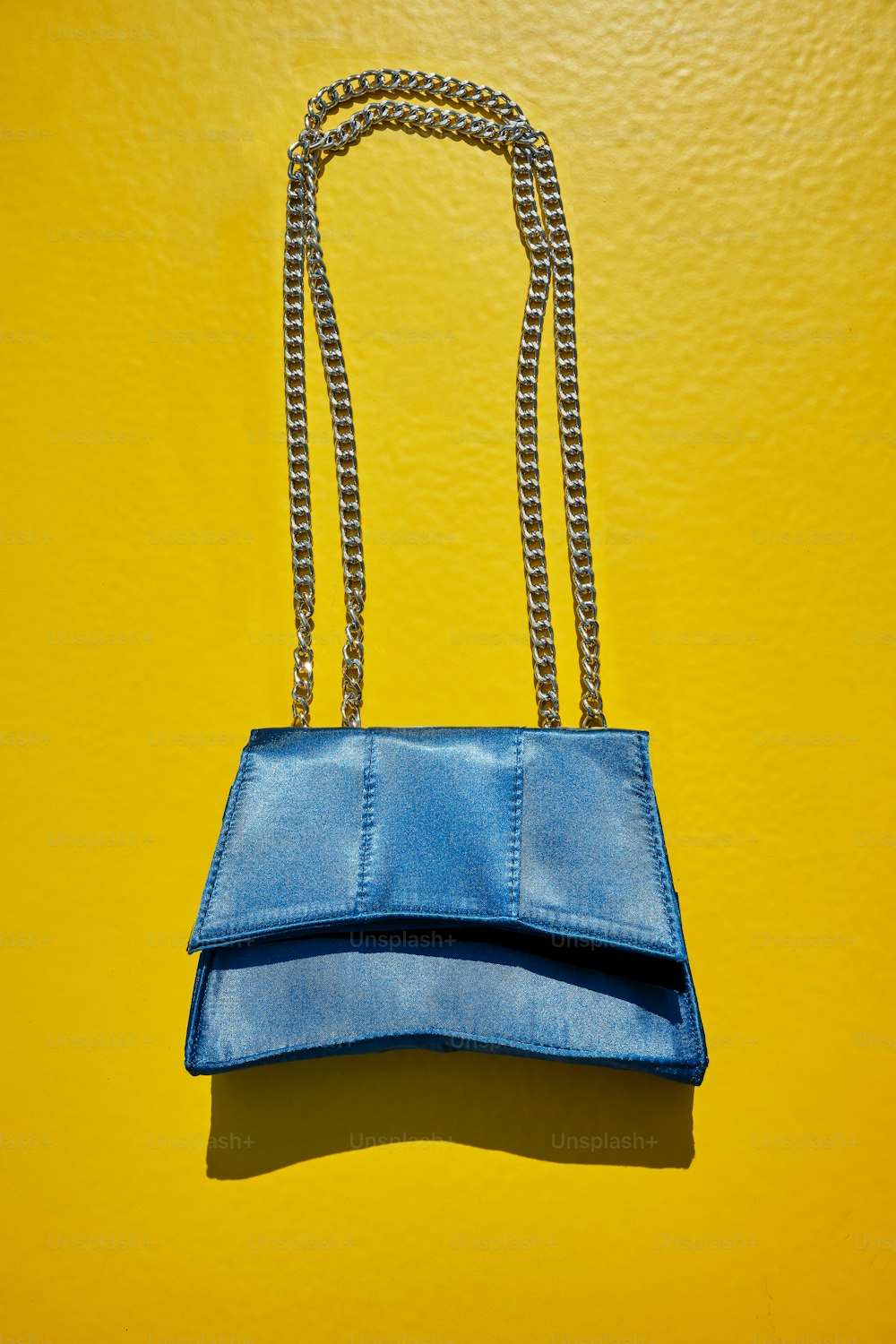 a blue purse hanging on a yellow wall