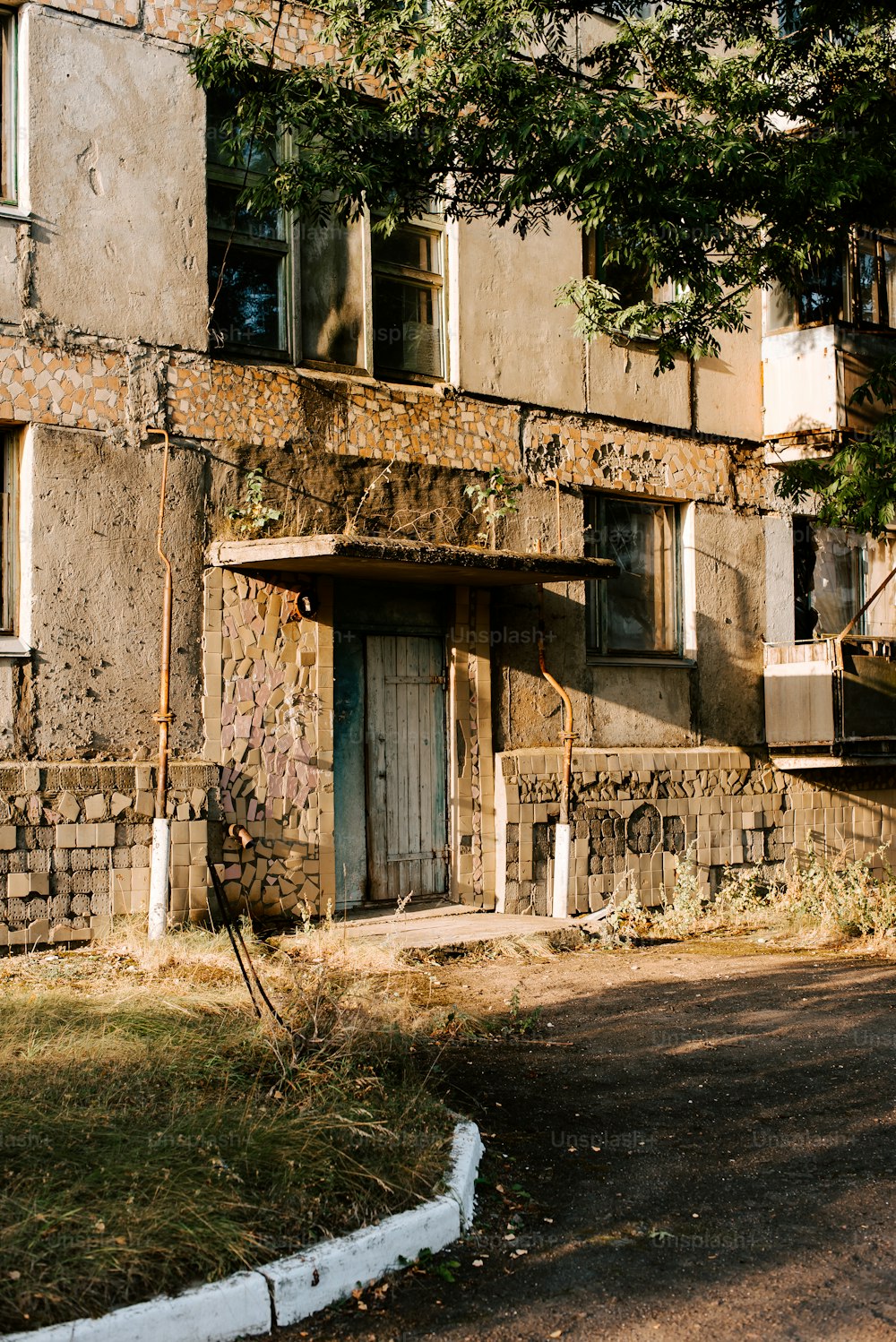 a run down building with a tree in front of it