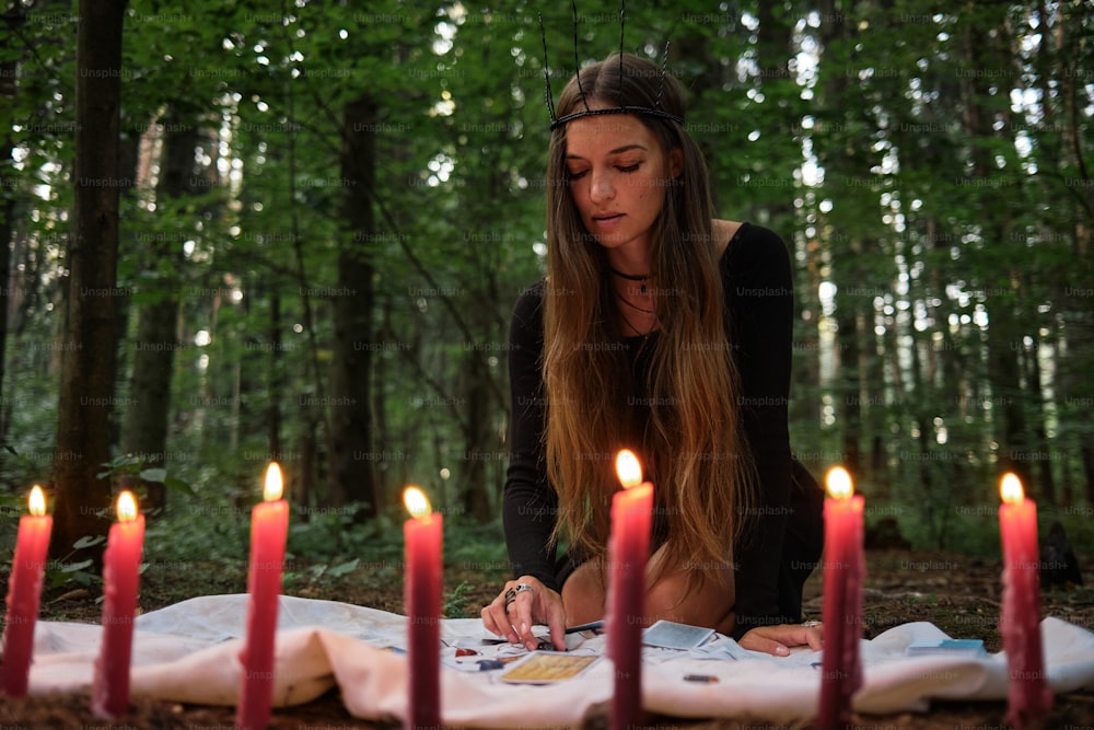 a woman sitting on the ground in front of a bunch of candles