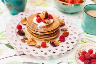 une pile de crêpes garnies de crème fouettée et de fruits