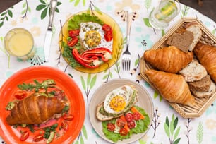 a table topped with plates of food and croissants