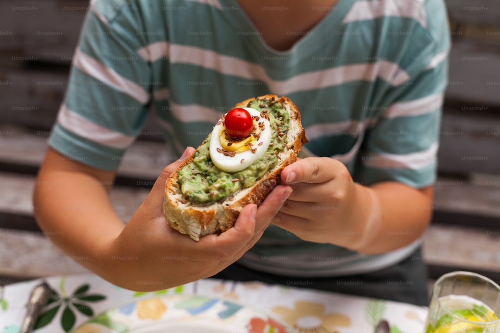 a person holding a piece of bread with an egg and guacamole on
