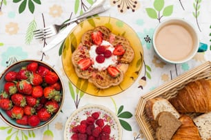 a table topped with plates of food and a bowl of strawberries