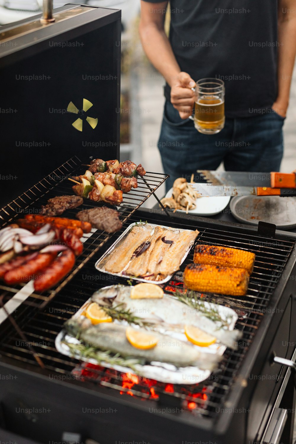 a man standing next to a grill filled with food