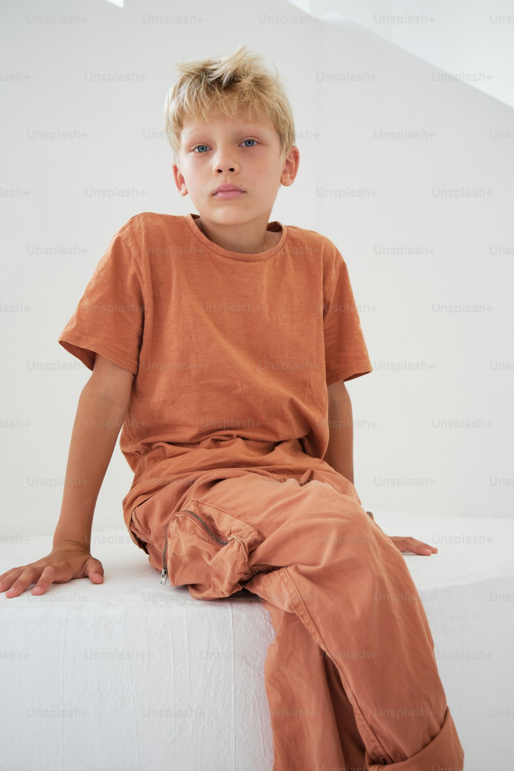 a young boy sitting on top of a white wall