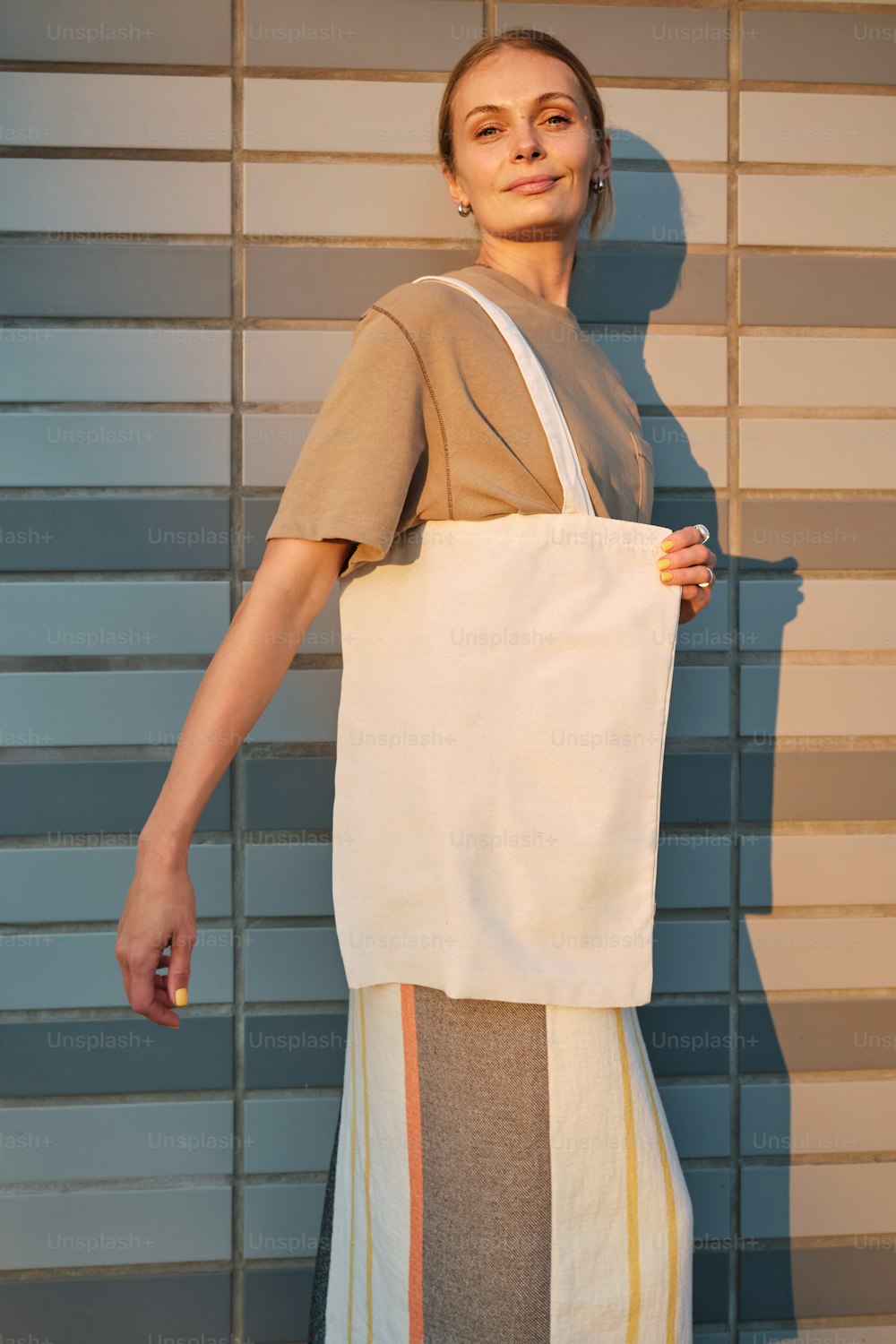 a woman holding a white bag in front of a wall
