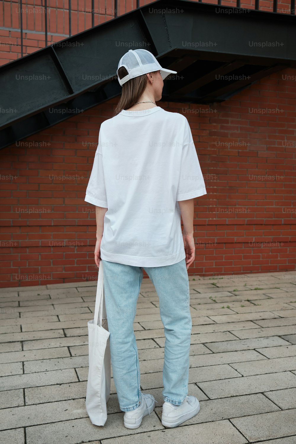 une personne debout sur un trottoir avec un sac blanc